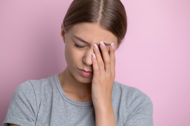 Schöne junge Frau, die starken Hauptschmerz glaubt