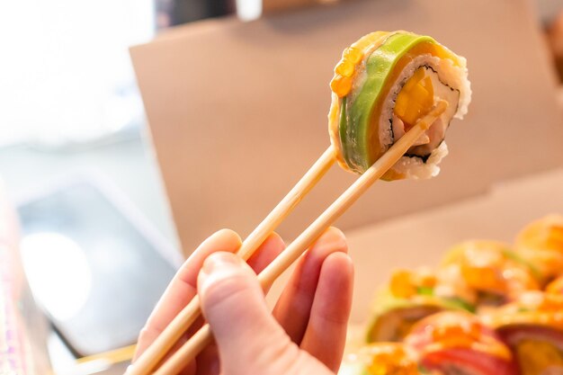 Schöne junge Frau, die Sushi-Rolle im Café isst. Frau, die Sushi-Set mit Essstäbchen im Restaurant isst.