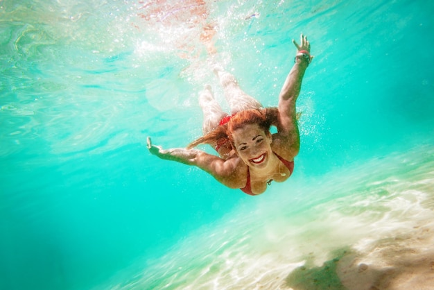 Schöne junge Frau, die unter Wasser im Meer taucht.