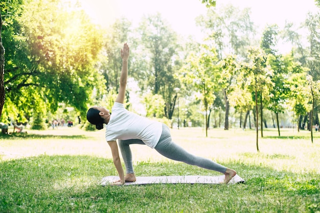 Schöne junge Frau, die Yoga im Park tut und wegschaut. Brünette Frau genießt die Natur bei einer Atemübung