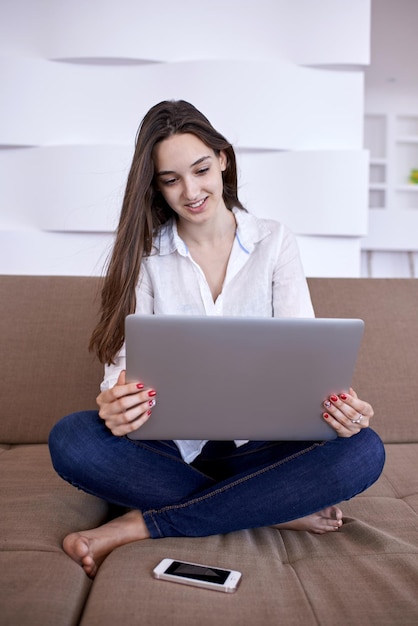 schöne junge frau entspannen und arbeiten am modernen home office der laptop-computer, während sie musin auf weißen kopfhörern hören