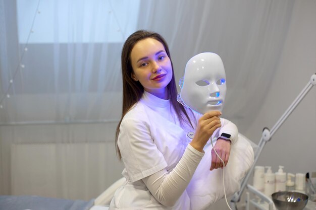 Foto schöne junge frau erhält eine led-lichttherapie-maskenbehandlung für ihr gesicht