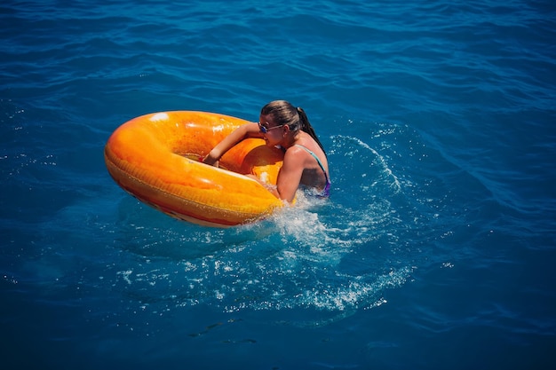Schöne junge Frau fiel aus einem aufblasbaren Kreis ins blaue Meer Mädchen im Urlaub schwimmt mit einem Kreis auf dem Meer