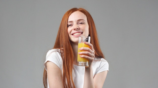 Schöne junge frau glücklich und orangensaft trinkend. junge frau, die glas orangensaft hält