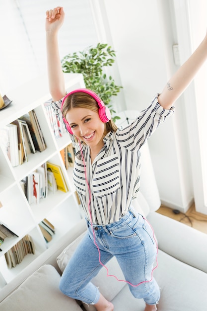 Schöne junge Frau hört Musik zu Hause.