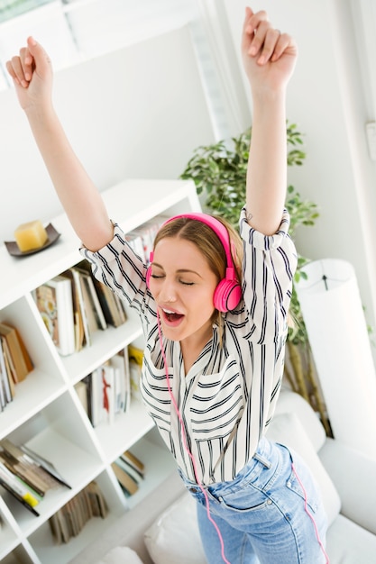 Schöne junge Frau hört Musik zu Hause.