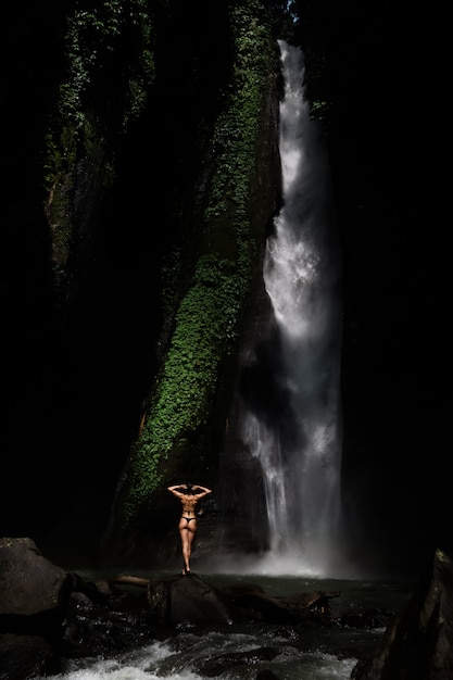 Schöne junge Frau im Bikini, der vor Wasserfall sich entspannt. Ökotourismus-Konzeptbild-Reisemädchen