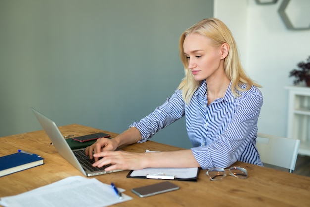 schöne junge Frau im Büro mit Laptop