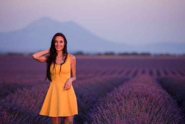 schöne junge frau im gelben kleid, das sich auf lila blumenlavendelfeld entspannt und spaß hat