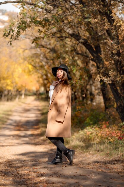 Schöne junge Frau im Mantel und im schwarzen Hut