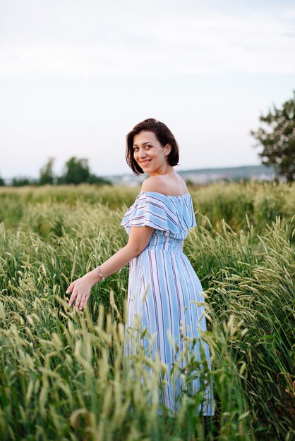 Schöne junge Frau im Sommer in einem Weizenfeld