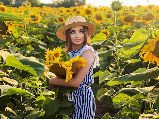 Schöne junge Frau im Sonnenblumenfeld am Sommertag