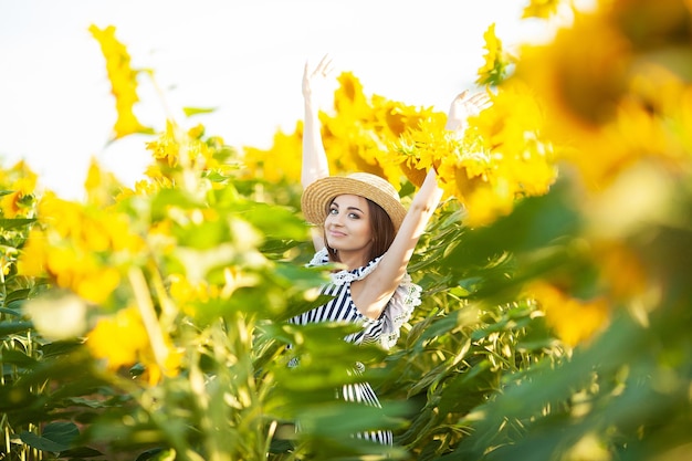 Schöne junge Frau im Sonnenblumenfeld am Sommertag