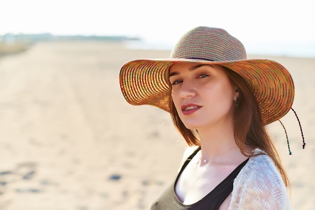 Schöne junge Frau im Strohhut am Strand