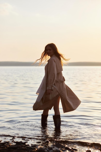 Schöne junge Frau im Wasser bei Sonnenuntergang Frau mit langen Haaren natürlicher Schönheit im See