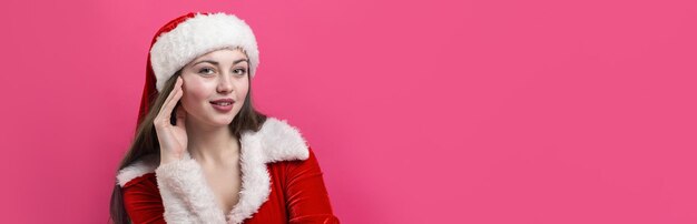 Schöne junge Frau im Weihnachtsmannkostüm vor dem roten Hintergrund