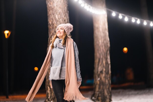 Schöne junge Frau im Winter Glückliche Winterzeit im Wald Festliche Girlande beleuchtet Weihnachten