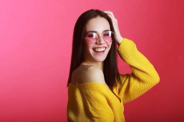 schöne junge Frau in der Sonnenbrille auf einem roten Hintergrund