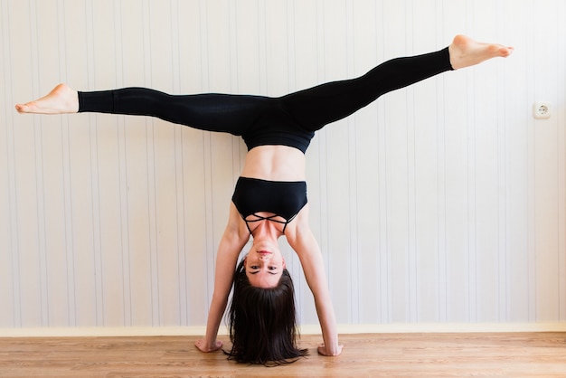 Schöne junge Frau in der Sportkleidung, die Yoga beim Entspannen zu Hause tut