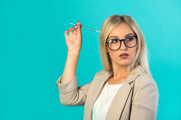 schöne junge Frau in einem Anzug auf Blau mit einem Stift in der Hand