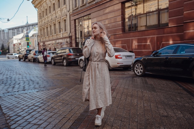 Schöne junge Frau in einem beigefarbenen Strickkleid geht durch die Straßen von Moskau, sonniges Frühlingswetter