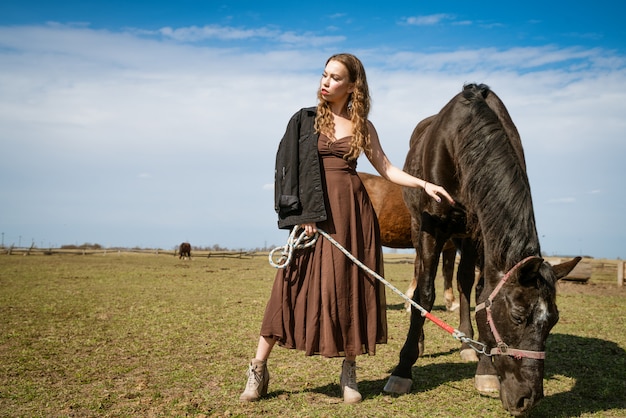 Schöne junge Frau in einem Feld mit Pferden. Attraktives Model.