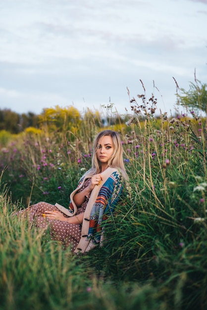 Schöne junge Frau in einem Hut und Kleid geht in der Natur im Herbst.