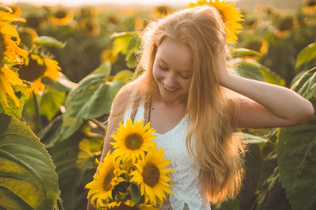 Schöne junge Frau in einem Sonnenblumenfeld. Porträt einer jungen Frau in der Sonne. Pollenallergie-Konzept