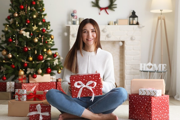 Schöne junge Frau in einem Weihnachtsinnenraum mit Geschenkplatz für Text