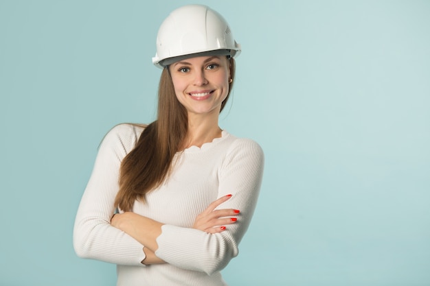 schöne junge Frau in einem weißen Helm auf einem blauen Hintergrund