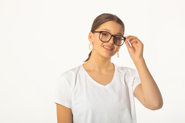 schöne junge Frau in einem weißen T-Shirt auf einem weißen Hintergrund, der Brille trägt
