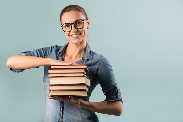 schöne junge Frau in Gläsern auf einem blauen Hintergrund mit Büchern