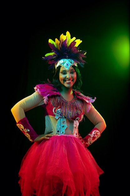 Schöne junge Frau in Karnevalsmaske und Maskeradenkostüm in bunten Lichtern