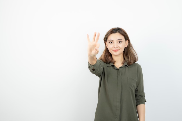 Schöne junge Frau in lässigem Outfit, die über einer weißen Wand steht. Foto in hoher Qualität