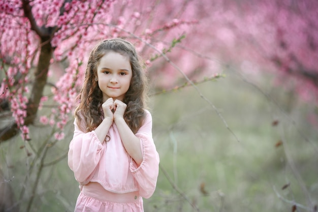 Schöne junge Frau in rosa stylischem Gartenkleid, das sakura blüht