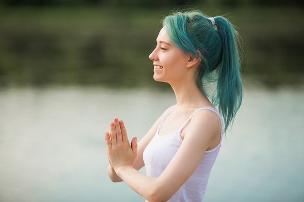 Schöne junge Frau in Sportbekleidung, die Yoga nahe dem See tut