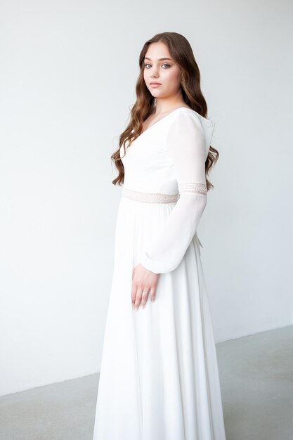 schöne junge Frau in weißem Hochzeitskleid mit langem lockigem Haar
