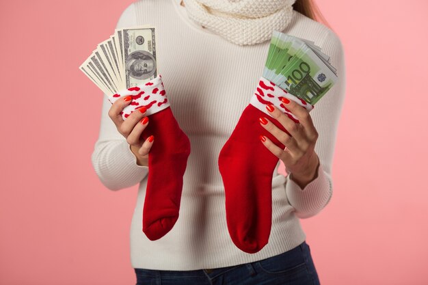 schöne junge Frau in Wintermütze mit roten Socken mit Geld