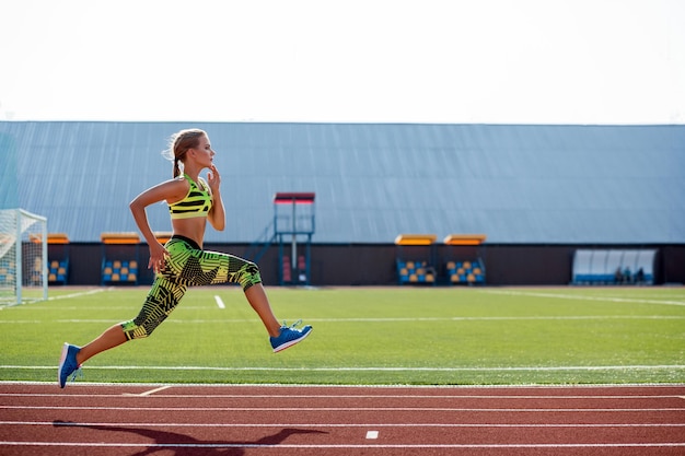 Schöne junge Frau joggt und läuft auf der Leichtathletikbahn im Stadion