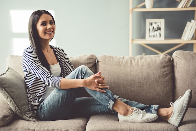 Schöne junge Frau lächelt beim Sitzen auf Couch