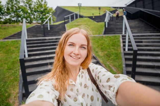 Schöne junge frau mit blonden haaren, die selfie am stadtstraßenhintergrund macht