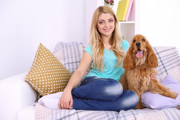 Schöne junge Frau mit Cocker Spaniel auf der Couch im Zimmer