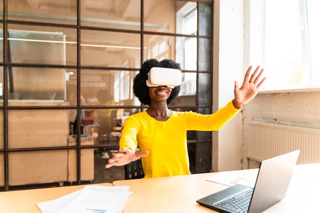 Schöne junge Frau mit dem Afro-Haarschnitt, die im Büro arbeitet