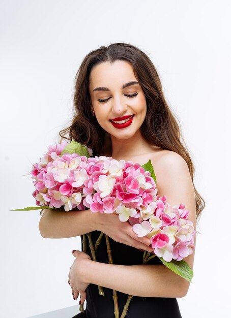 Schöne junge Frau mit einem Blumenstrauß auf weißem Hintergrund