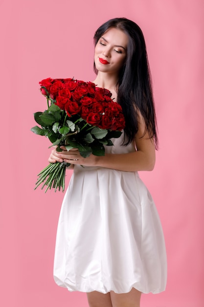 Schöne junge Frau mit einem großen Strauß roter Rosen