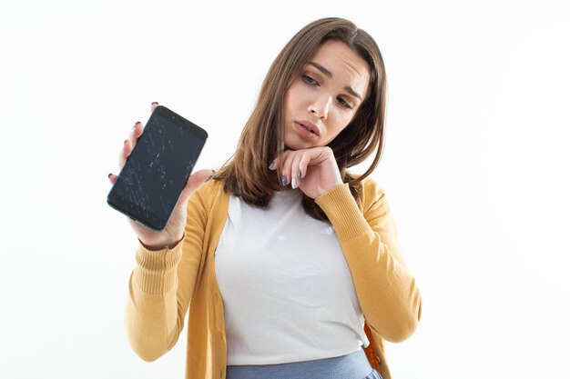 Schöne junge Frau mit einem kaputten Telefon