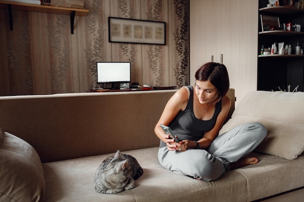 Schöne junge Frau mit einer Hauskatze auf der Couch