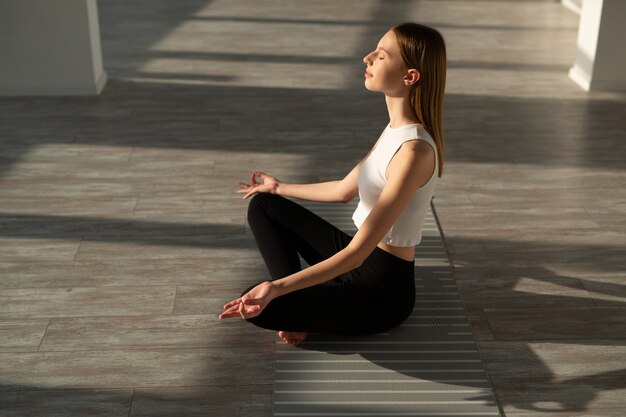 schöne junge Frau mit einer schlanken Figur beschäftigt sich mit Yoga in der Halle