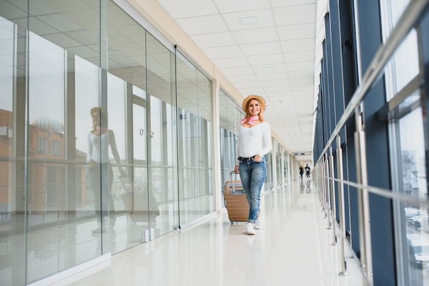 Schöne junge Frau mit Gepäck am Flughafen