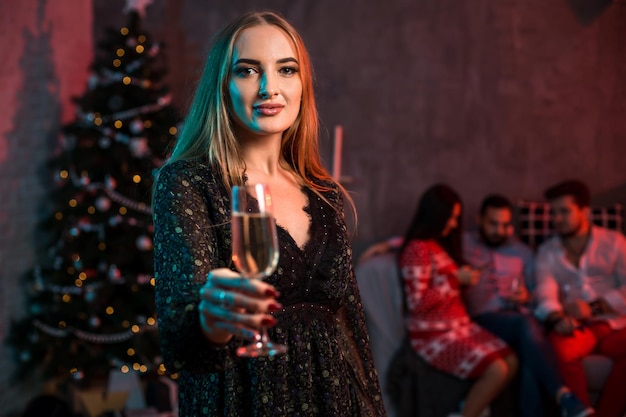 Schöne junge Frau mit Glas Champagner bei Weihnachtsfeier